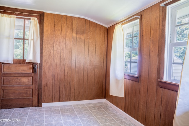 empty room featuring tile patterned flooring, wooden walls, and ornamental molding