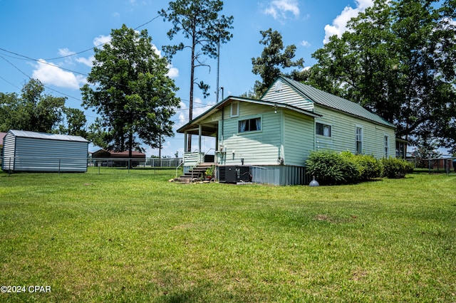 view of home's exterior with central air condition unit, a yard, and a storage shed