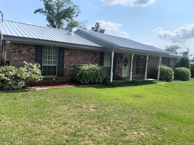 4908 Davis Dr, Marianna, FL 32446 - ranch-style house with brick siding, metal roof, and a front lawn