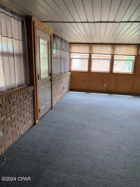 4908 Davis Dr, Marianna, FL 32446 - unfurnished room featuring brick wall, wood walls, and carpet