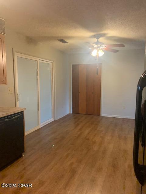 unfurnished dining area with ceiling fan, hardwood / wood-style flooring, and a textured ceiling