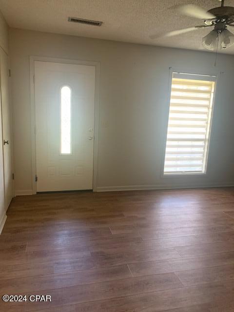 entrance foyer with a textured ceiling, ceiling fan, and wood-type flooring