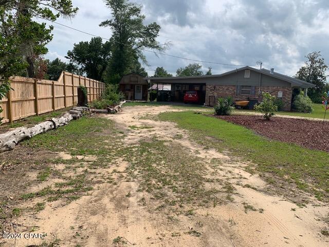 4908 Davis Dr, Marianna, FL 32446 - view of yard with fence, an attached carport, and dirt driveway