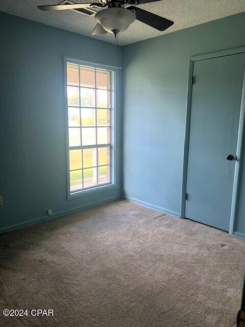 spare room with a textured ceiling, ceiling fan, and carpet flooring