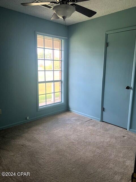 4908 Davis Dr, Marianna, FL 32446 - carpeted spare room with a textured ceiling, ceiling fan, and baseboards
