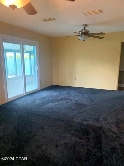 4908 Davis Dr, Marianna, FL 32446 - spare room with a ceiling fan, a textured ceiling, dark colored carpet, and visible vents