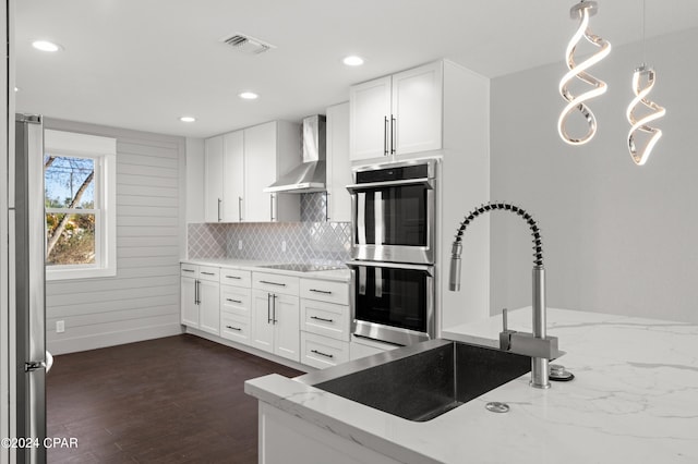 kitchen with white cabinets, dark hardwood / wood-style floors, wall chimney exhaust hood, and appliances with stainless steel finishes