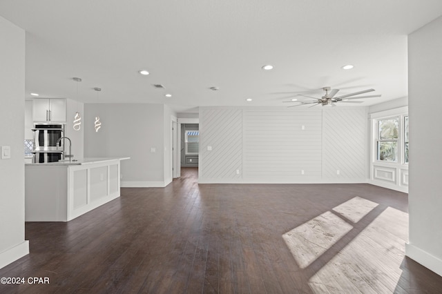 unfurnished living room featuring dark hardwood / wood-style flooring and ceiling fan