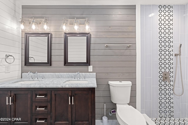 bathroom featuring dual vanity, toilet, and wooden walls