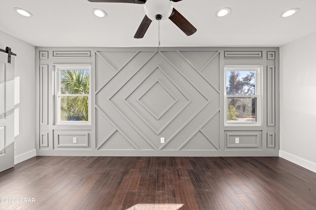 interior space with a wealth of natural light, dark hardwood / wood-style floors, and a barn door