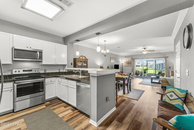 kitchen featuring kitchen peninsula, stainless steel appliances, sink, decorative light fixtures, and white cabinetry