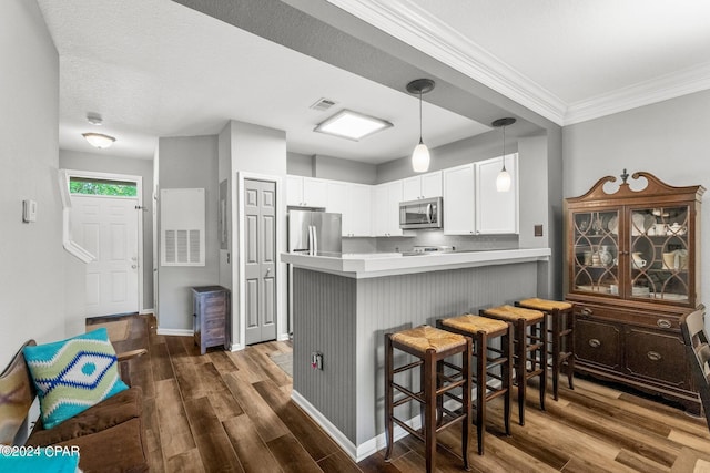 kitchen with white cabinetry, hanging light fixtures, stainless steel appliances, a kitchen breakfast bar, and kitchen peninsula