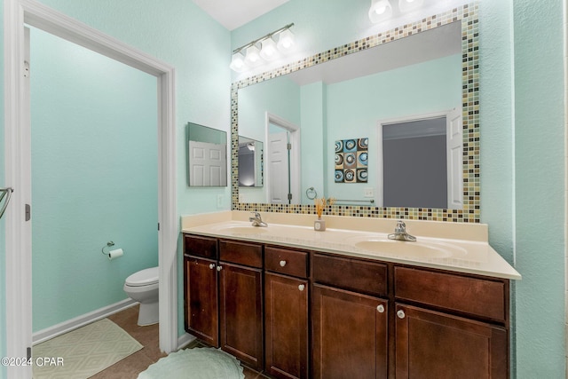 bathroom featuring vanity, toilet, and tasteful backsplash