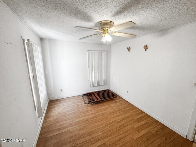 spare room featuring a wealth of natural light, ceiling fan, a textured ceiling, and hardwood / wood-style flooring