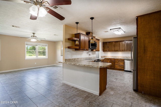 kitchen featuring a textured ceiling, kitchen peninsula, ceiling fan, stainless steel appliances, and pendant lighting