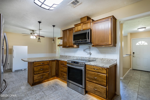 kitchen featuring decorative backsplash, hanging light fixtures, kitchen peninsula, stainless steel appliances, and ceiling fan