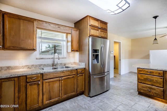 kitchen featuring hanging light fixtures, sink, stainless steel fridge, tasteful backsplash, and ceiling fan