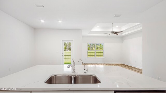 kitchen with light hardwood / wood-style flooring, stainless steel appliances, white cabinets, sink, and light stone countertops