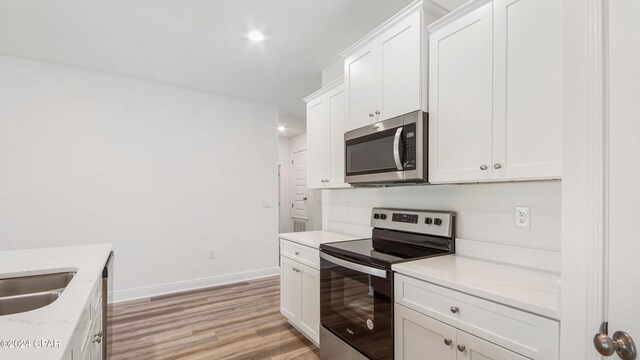 kitchen with ceiling fan, a tray ceiling, light wood-type flooring, sink, and light stone countertops