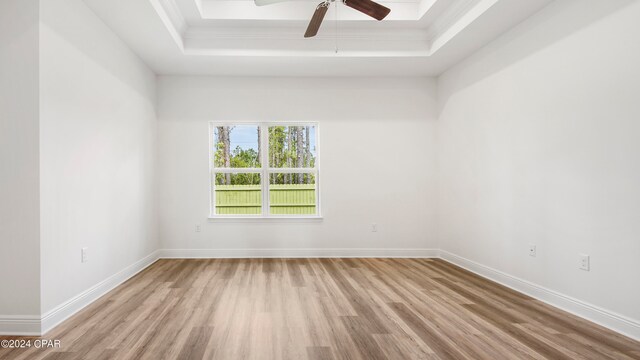 unfurnished living room with light wood-type flooring, ceiling fan, and a raised ceiling