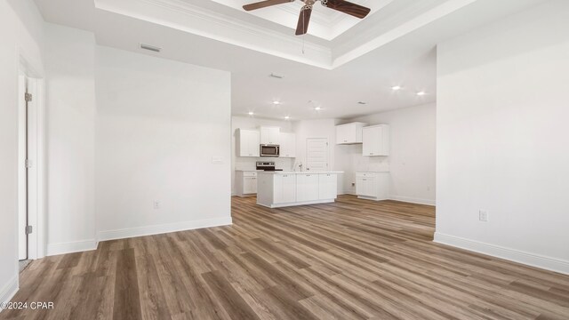 carpeted spare room with ceiling fan, crown molding, and a tray ceiling