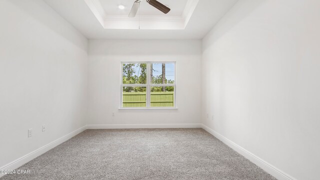 unfurnished bedroom featuring light carpet, a raised ceiling, ensuite bathroom, and ornamental molding