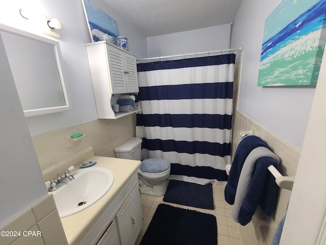 bathroom with tile walls, toilet, vanity, and a textured ceiling