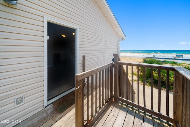 wooden deck featuring a beach view and a water view