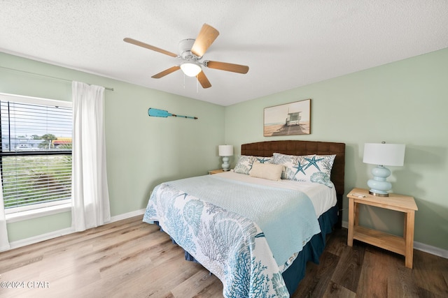 bedroom featuring ceiling fan, hardwood / wood-style flooring, and a textured ceiling