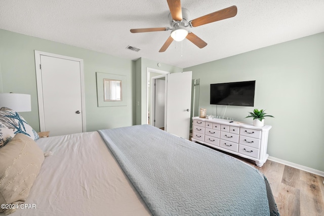 bedroom with ceiling fan, light hardwood / wood-style flooring, and a textured ceiling