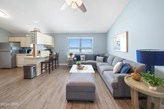 living room with ceiling fan, light hardwood / wood-style floors, and vaulted ceiling