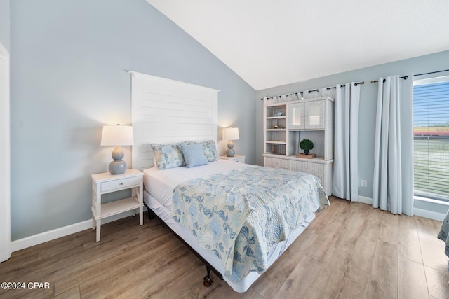 bedroom with lofted ceiling and light wood-type flooring