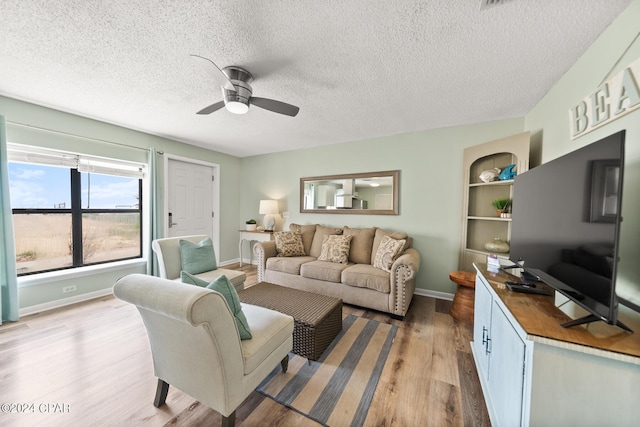 living room with hardwood / wood-style floors, built in features, a textured ceiling, and ceiling fan