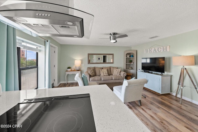 living room featuring ceiling fan, hardwood / wood-style floors, and a textured ceiling