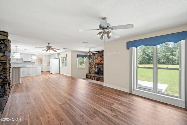 unfurnished living room with a fireplace, a textured ceiling, and light hardwood / wood-style flooring