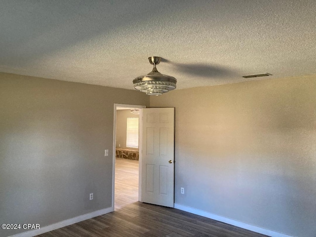 empty room with a textured ceiling and dark hardwood / wood-style flooring