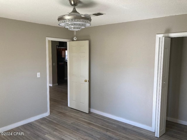 unfurnished bedroom with a textured ceiling and dark wood-type flooring