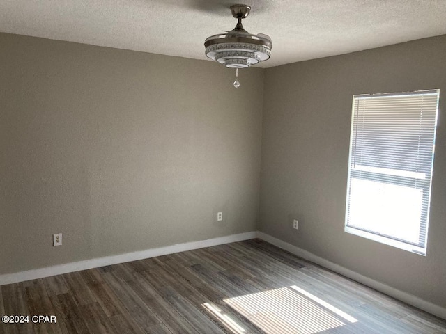 empty room with hardwood / wood-style floors, a textured ceiling, and an inviting chandelier