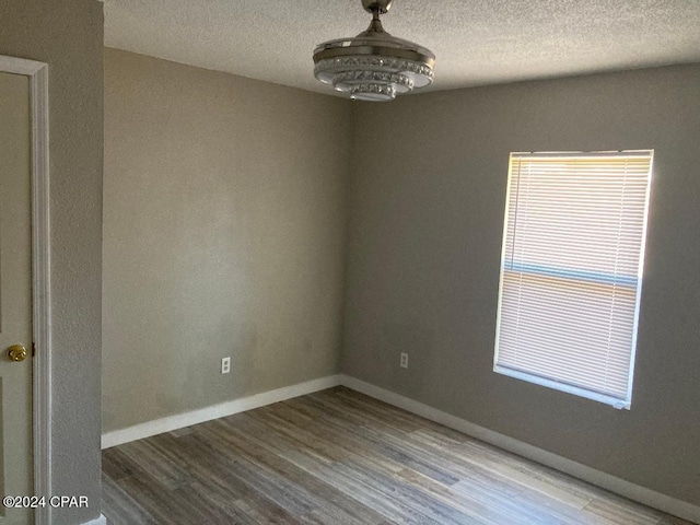 unfurnished room with wood-type flooring and a textured ceiling