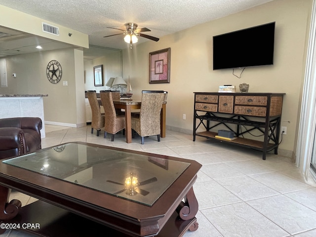 dining area featuring ceiling fan, light tile patterned flooring, and a textured ceiling