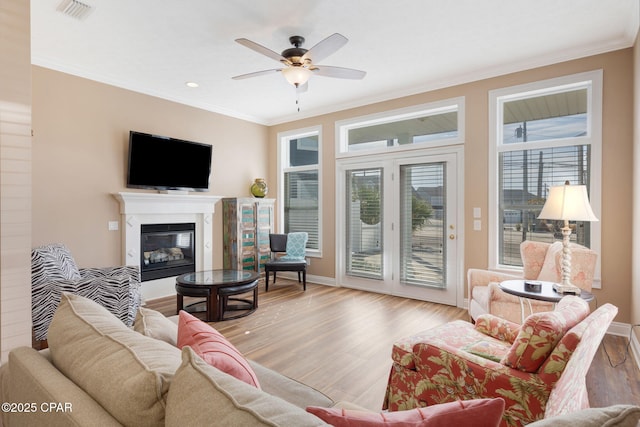 living room featuring light hardwood / wood-style flooring, ornamental molding, and a healthy amount of sunlight