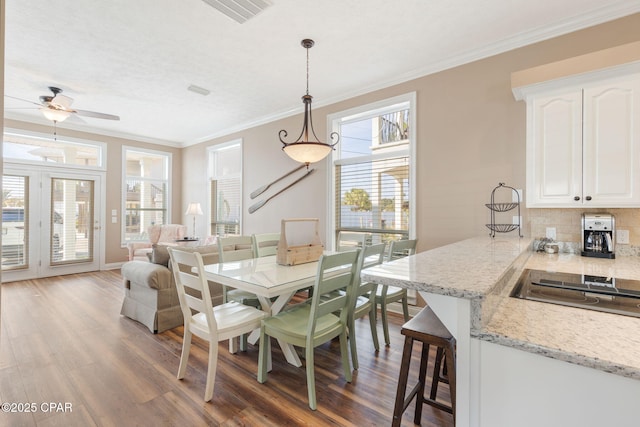 dining space featuring wood-type flooring, ornamental molding, and ceiling fan