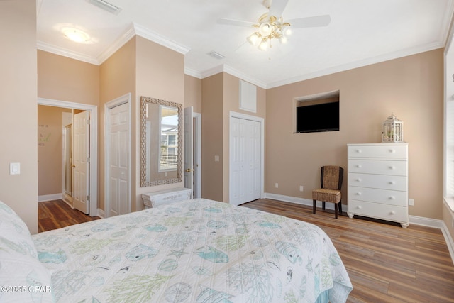 bedroom featuring crown molding, hardwood / wood-style flooring, and multiple closets