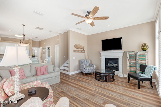 living room featuring light hardwood / wood-style flooring, ornamental molding, and ceiling fan