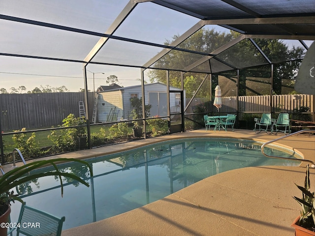 view of swimming pool featuring a patio, glass enclosure, and a shed