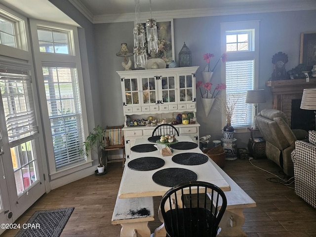 dining room featuring ornamental molding, a brick fireplace, a notable chandelier, and dark wood-type flooring