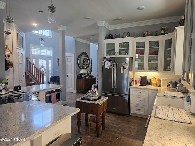 kitchen featuring pendant lighting, stainless steel appliances, white cabinets, and decorative columns