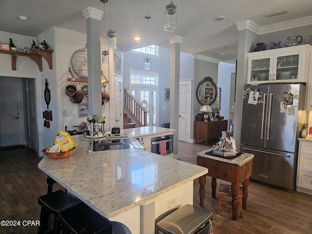 kitchen featuring hanging light fixtures, high quality fridge, a kitchen island, white cabinetry, and decorative columns