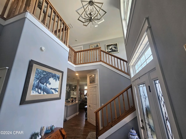 entryway with an inviting chandelier, a towering ceiling, and dark hardwood / wood-style flooring