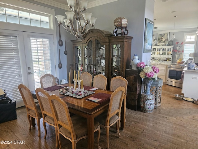 dining room with an inviting chandelier, light wood-type flooring, a healthy amount of sunlight, and crown molding